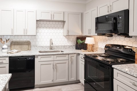 a kitchen with white cabinets and black appliances